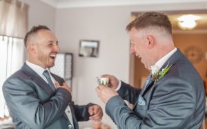 Best man helping the Groom with his button hole.